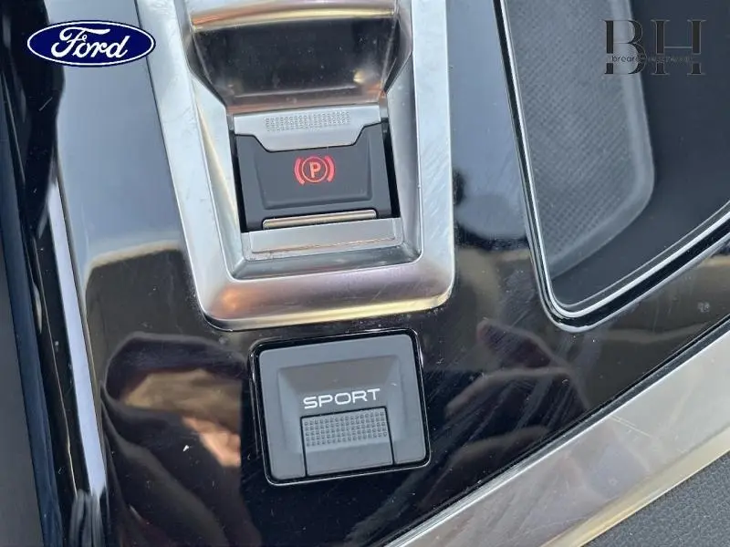 Gros plan sur la console centrale noire brillante avec bouton Sport et frein à main électrique du Peugeot 5008 gris Artense.