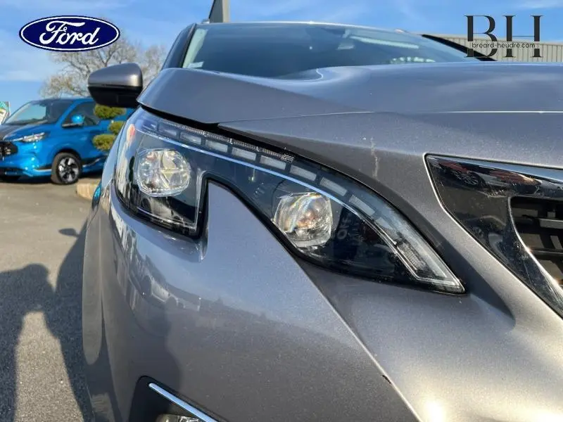 Gros plan sur le phare avant gauche du Peugeot 5008 gris Artense, mettant en valeur le design moderne et les lignes du capot.