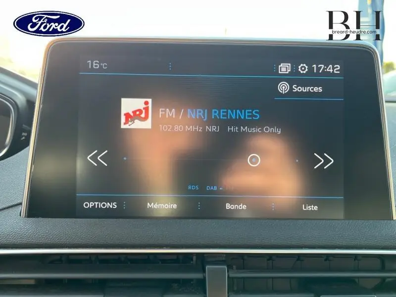 Écran tactile central affichant la radio NRJ dans un Ford, vue de face du tableau de bord intérieur.