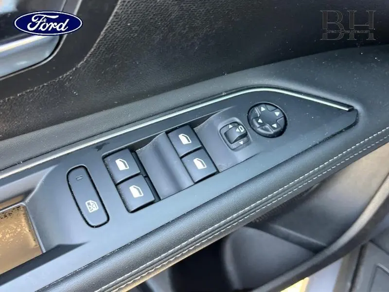 Panneau de commandes des vitres et rétroviseurs côté conducteur en plastique noir avec surpiqûres blanches, intérieur Ford.