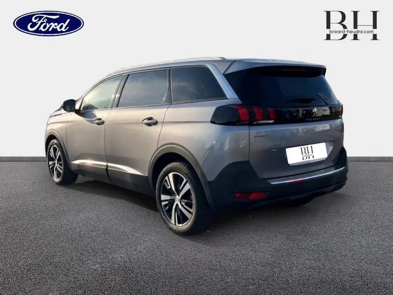 Vue 3/4 arrière droite d'un Peugeot 5008 gris Artense avec jantes alu et vitres arrière surteintées.