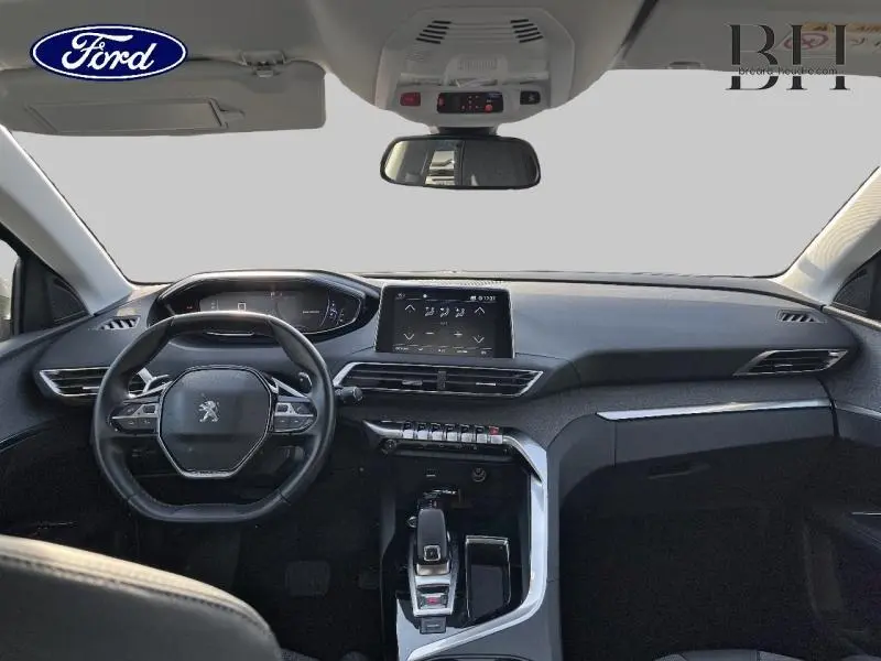 Vue intérieure avant du Peugeot 5008 gris Artense, mettant en valeur le tableau de bord moderne et l'écran tactile central.