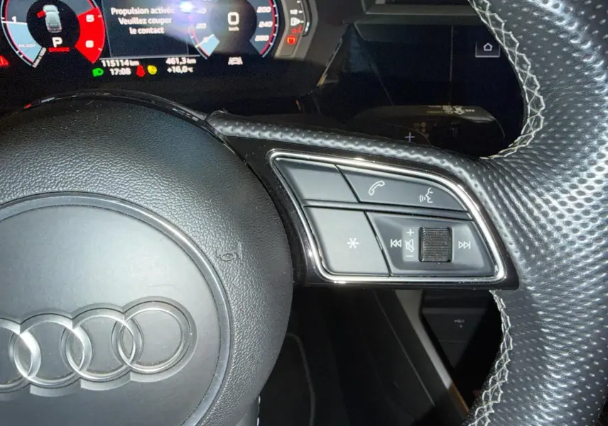 Gros plan sur le volant en cuir perforé de l'Audi A3 bleu 2022, avec commandes intégrées côté droit.