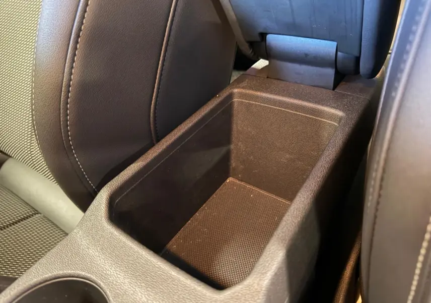 Gros plan sur le rangement central entre les sièges avant en tissu noir de l’Audi A3 2.0 TDI S-Line 2022.