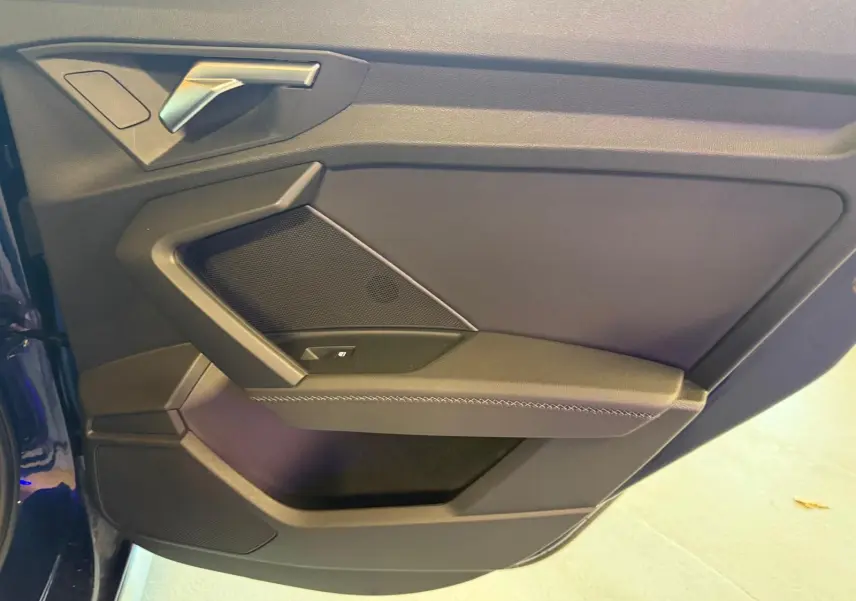 Vue rapprochée de la porte avant gauche de l'Audi A3 2.0 TDI S-Line bleu, avec poignée argentée et panneau noir.