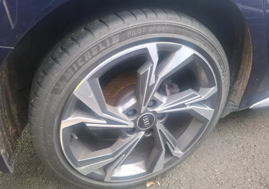 Gros plan sur la roue avant gauche d'une Audi A3 bleu 2022 avec jante alliage au design moderne.