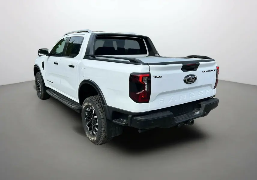 Ford Ranger 2025 blanc glacier vu 3/4 arrière droit avec arceau sport, jantes alu noires et rideau coulissant.