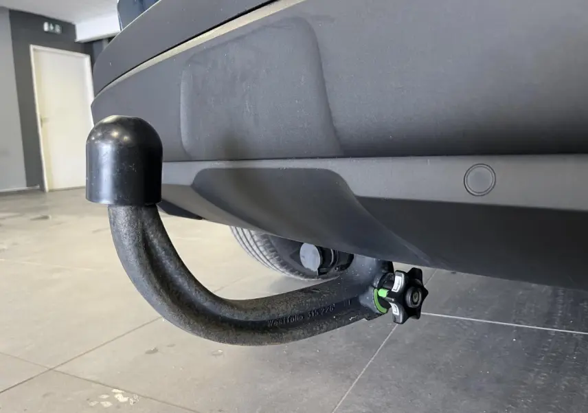 Gros plan sur l'attelage démontable noir sous le pare-chocs arrière du Peugeot 3008 bleu 2022.