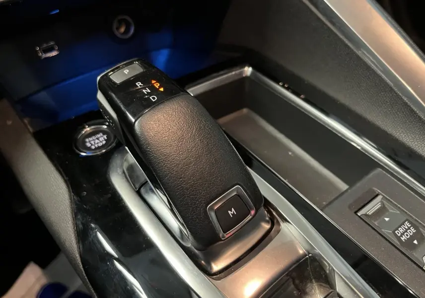 Le levier de vitesse automatique noir du Peugeot 3008 2022 avec bouton mode manuel, entouré de la console brillante.