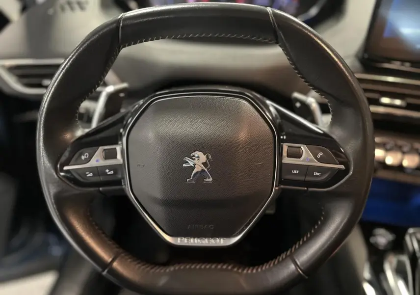 Volant compact en cuir noir du Peugeot 3008 2022 avec commandes intégrées et logo lion central chromé.