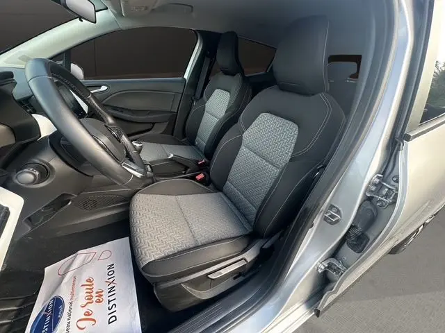 Vue intérieure côté conducteur de la Renault Clio V gris Highland, sièges tissu gris noir avec volant multifonction TEP.