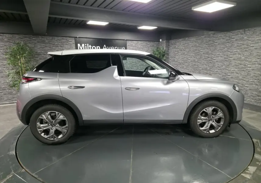 Vue de profil droit du DS3 Crossback gris métallisé avec toit blanc, jantes alliage et poignées affleurantes.