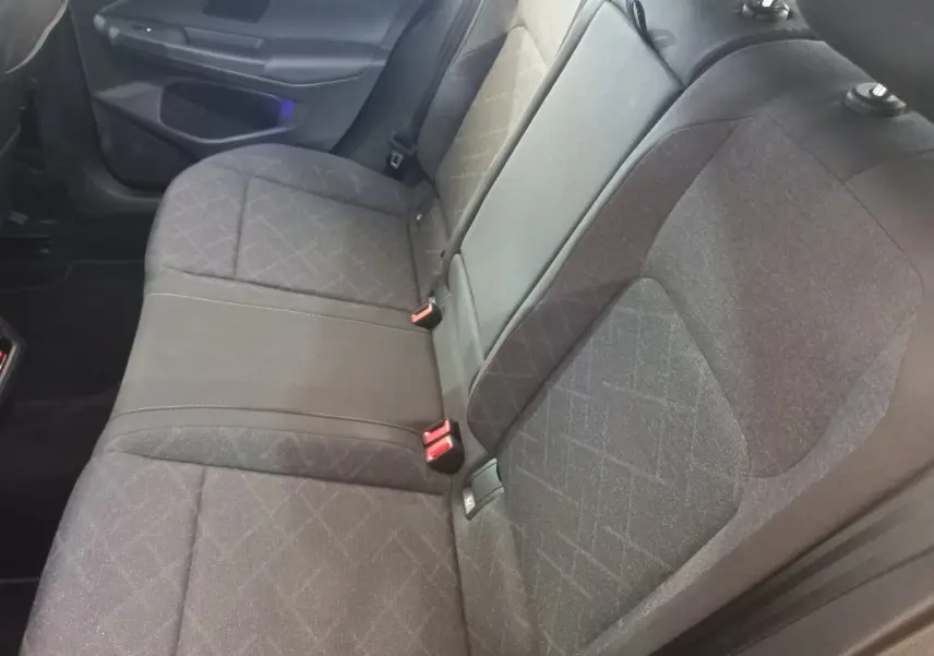 Vue intérieure côté droit des sièges arrière gris foncé de la Volkswagen Golf 1.5 ETSI 2022 avec ceinture rouge.