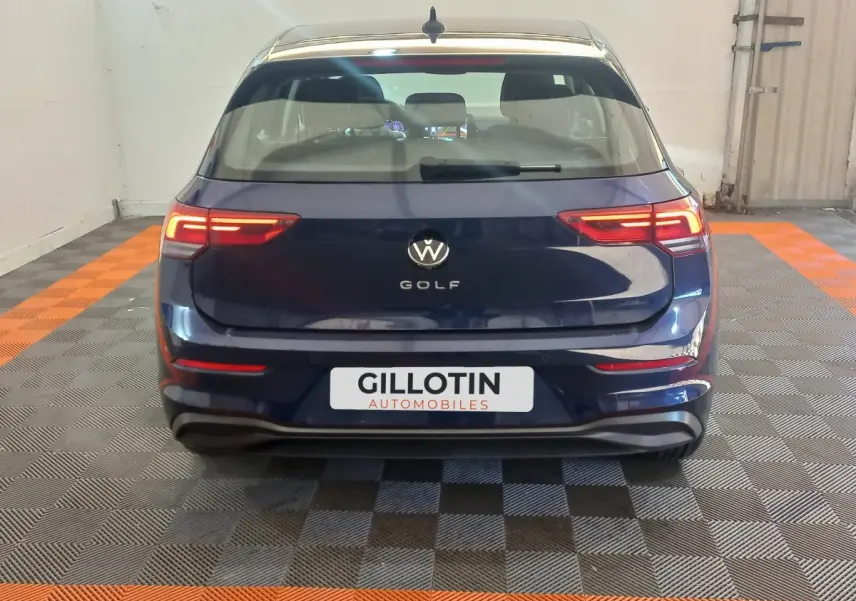 Vue arrière d'une Volkswagen Golf bleu foncé avec feux arrière LED allumés dans un garage.