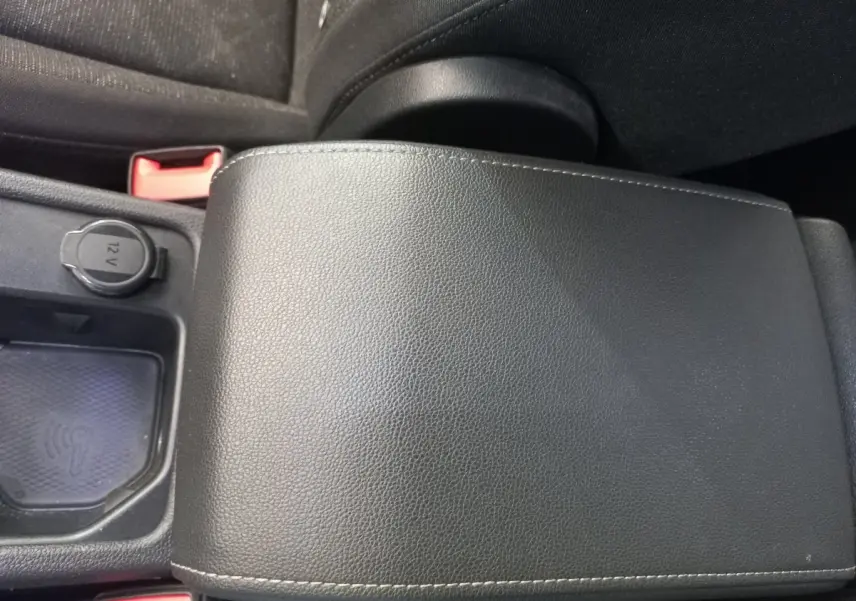 Gros plan sur l'accoudoir central en cuir noir et prise 12V dans l'habitacle d'une Volkswagen Golf 2022.