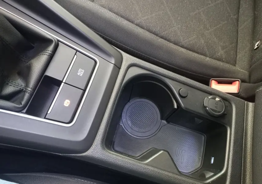 Gros plan sur la console centrale noire de la Volkswagen Golf 1.5 ETSI avec zone de recharge sans fil et prise 12V.