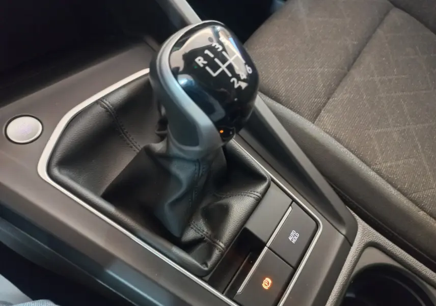 Gros plan sur levier de vitesse manuel noir et console centrale avec bouton démarrage dans Volkswagen Golf bleu 2022