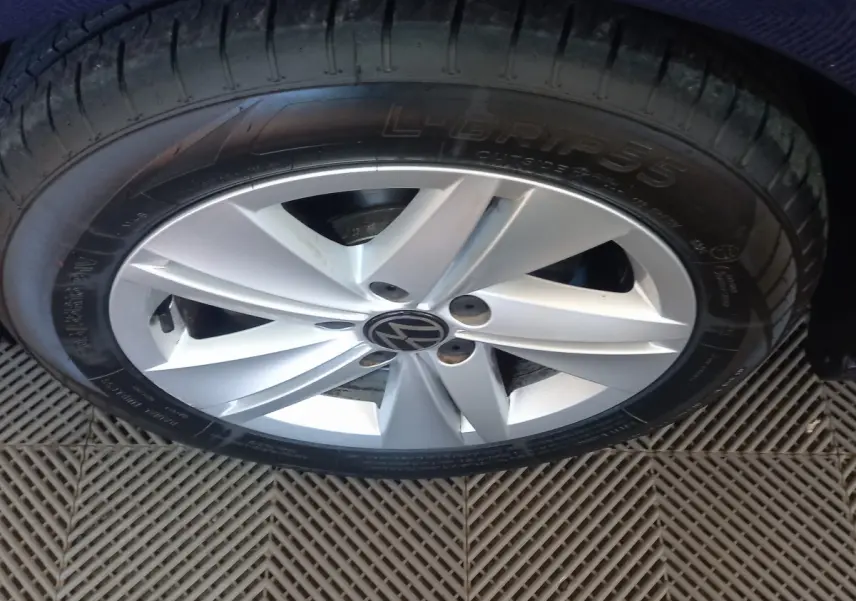 Gros plan sur la roue avant droite d'une Volkswagen Golf bleu, jante alliage argentée avec logo VW central.