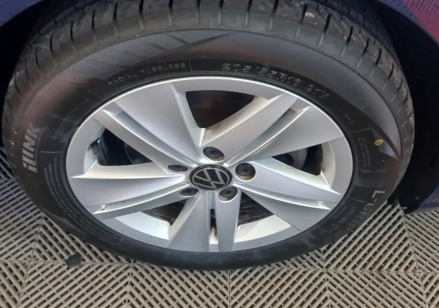 Gros plan sur la roue avant droite d'une Volkswagen Golf bleu, jante alliage argentée avec logo VW central.