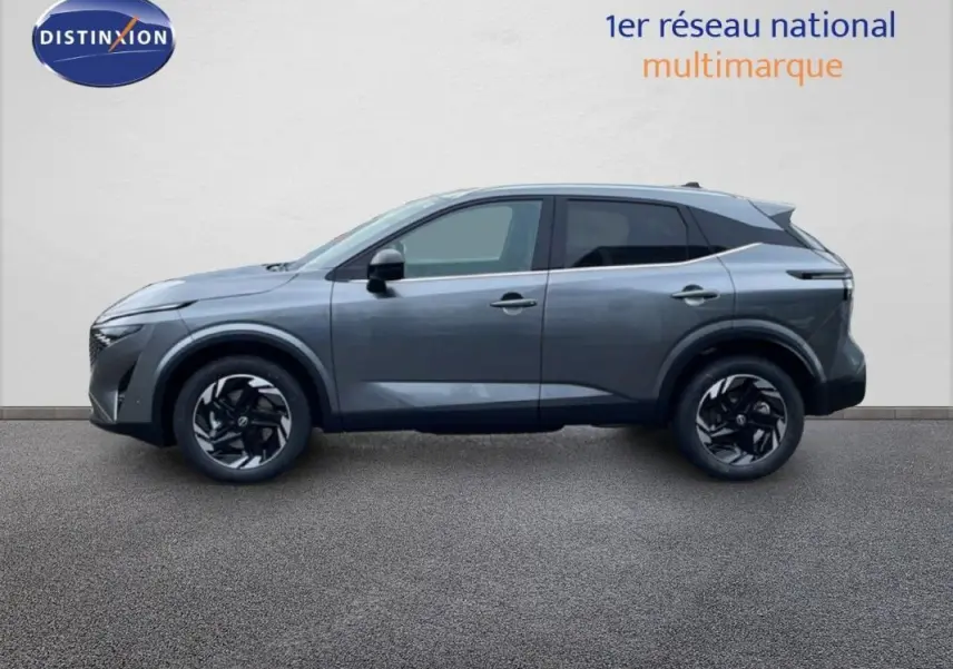 Vue de profil côté gauche d'un Nissan Qashqai gris 2025 avec jantes aluminium noires et barres de toit visibles.
