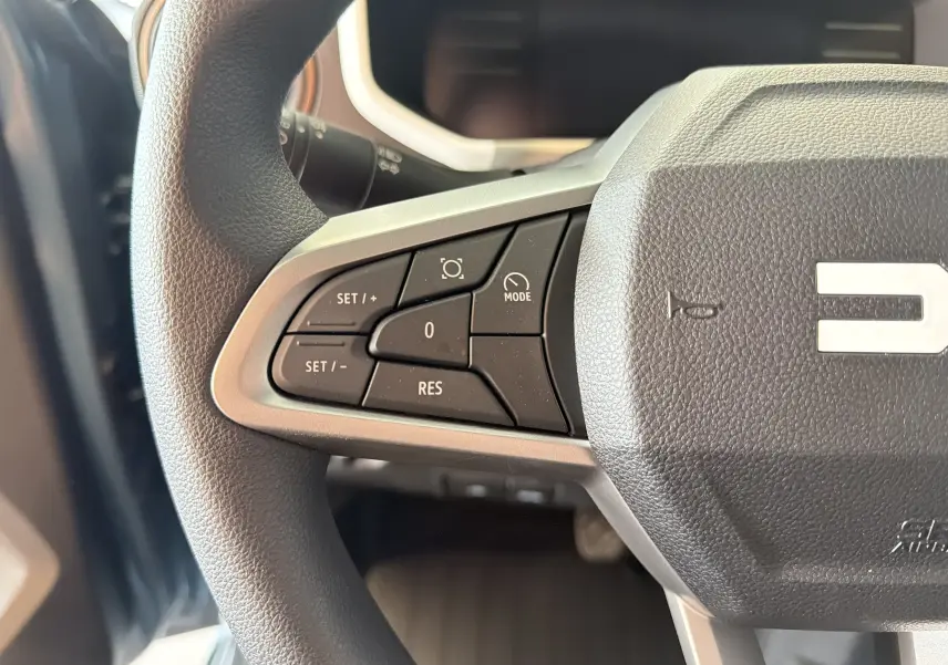 Gros plan sur le volant côté gauche du Dacia Spring 65 Extreme 2026 bleu ardoise, montrant les commandes de régulateur de vitesse.