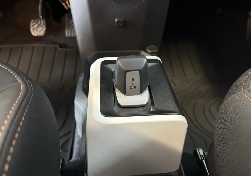 Gros plan sur le levier de vitesses automatique de la Dacia Spring 65 Extreme 2026, intérieur noir et beige avec surpiqûres orange.