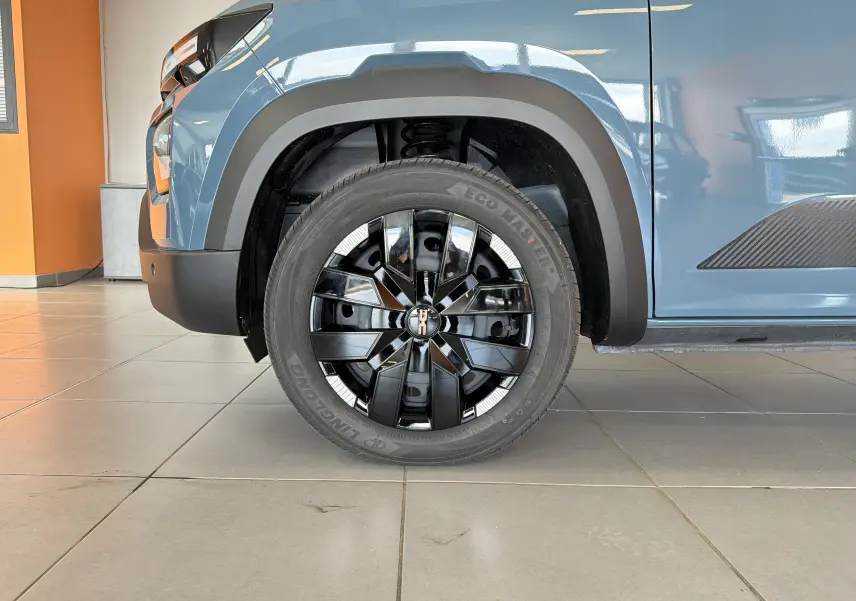 Gros plan sur la roue avant droite du Dacia Spring 65 Extreme bleu ardoise avec jante noire brillante et détails modernes.