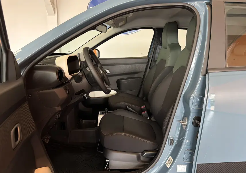 Vue intérieure côté conducteur de la Dacia Spring 65 Extreme 2026 bleu ardoise, avec sièges noirs et tableau de bord minimaliste.