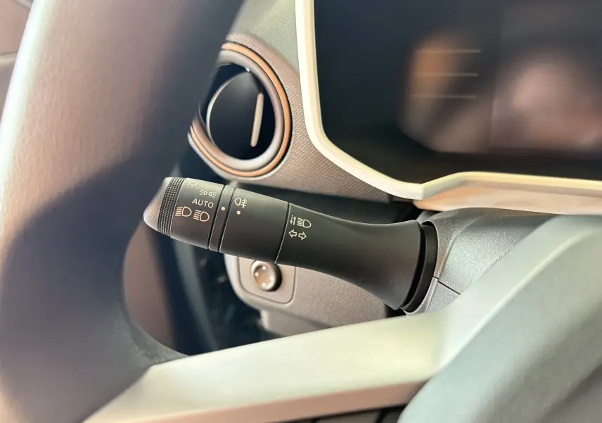 Détail intérieur du commodo d'éclairage à gauche du volant dans une Dacia Spring 65 Extreme 2026 bleu ardoise.