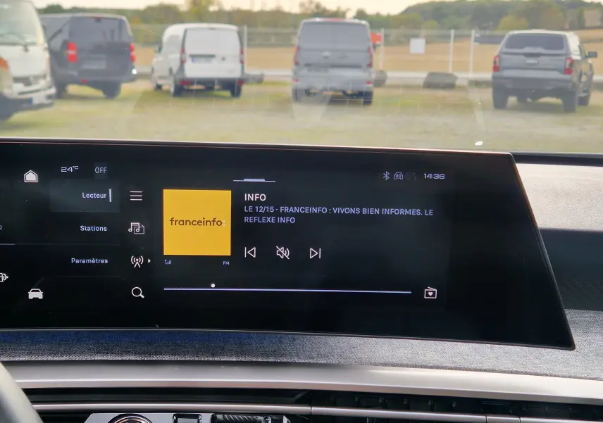 Vue intérieure du tableau de bord du Peugeot 3008 2025 gris Artense, écran tactile panoramique affichant une radio FM.