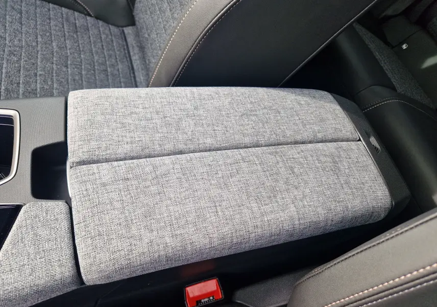 Gros plan sur l'accoudoir central en tissu gris clair et cuir noir du Peugeot 3008 1.2 HYBRID 145 2025.