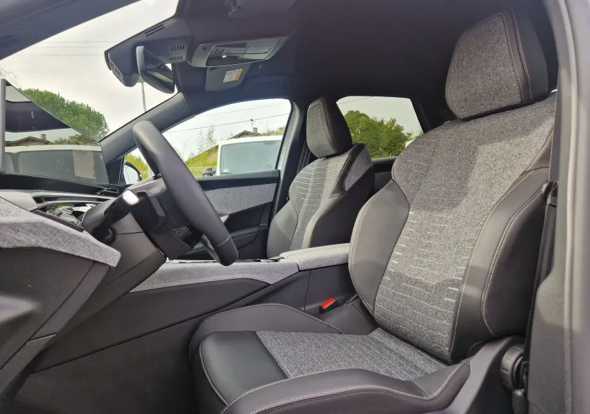 Vue intérieure côté conducteur du Peugeot 3008 2025 gris Artense, sièges tissu et cuir avec écran panoramique visible.