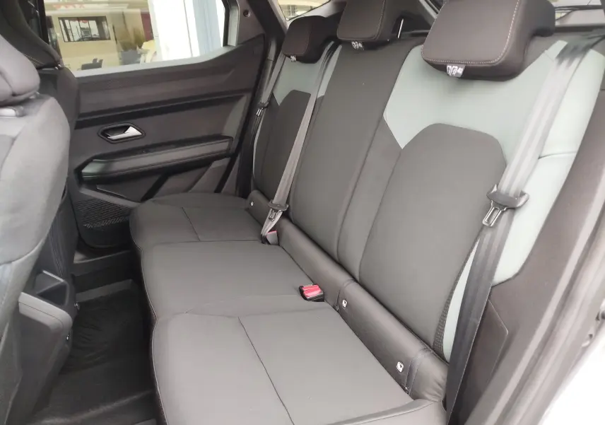 Vue latérale droite de l'intérieur arrière du Dacia Duster 2025, sièges tissu gris foncé avec appuie-têtes intégrés.