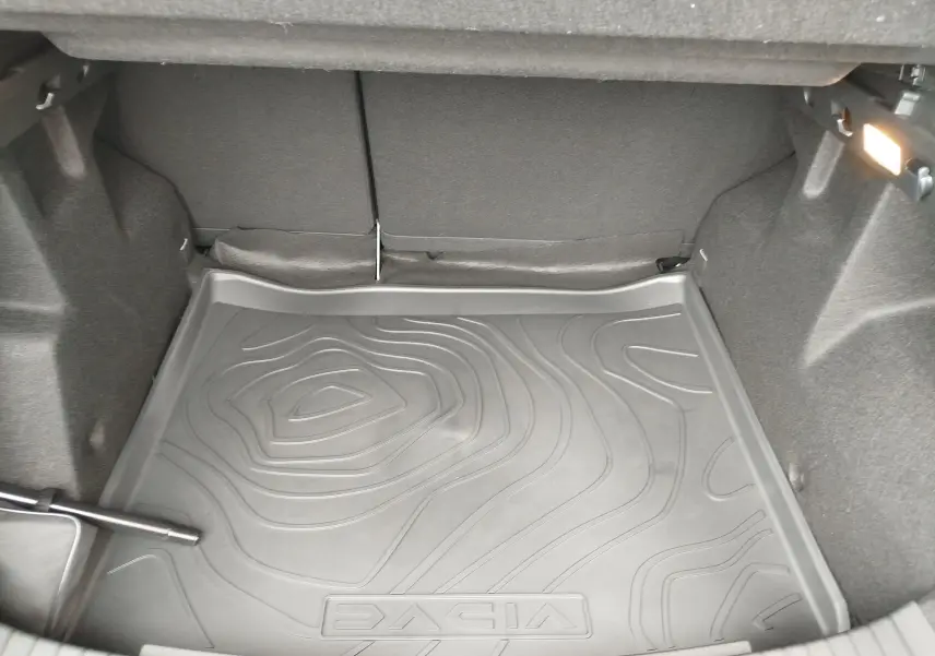 Coffre du Dacia Duster gris schiste 2025, vue intérieure montrant le tapis de sol avec logo DACIA embossé.