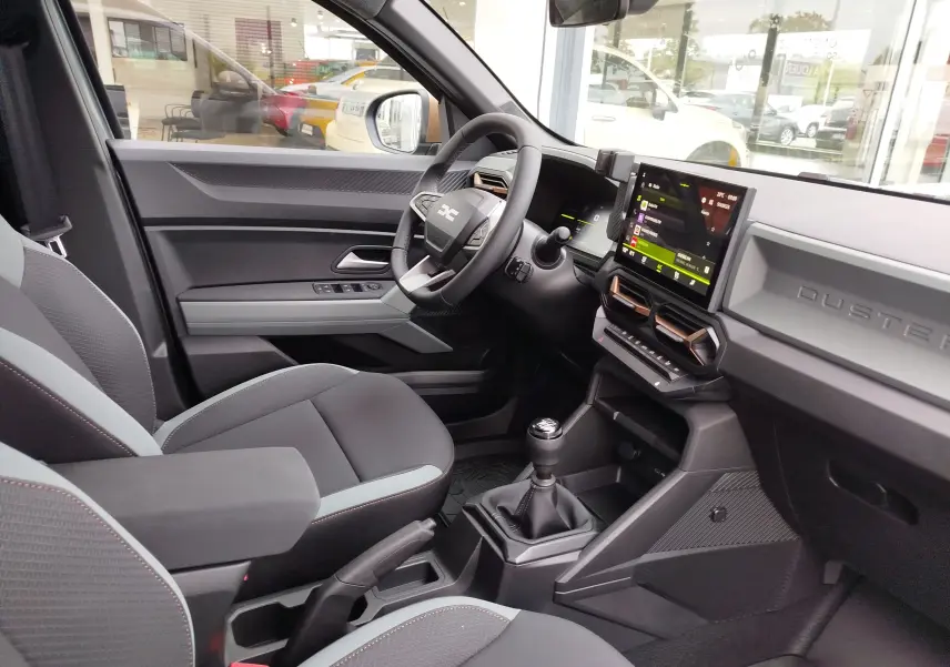 Intérieur côté conducteur du Dacia Duster 2025 gris schiste, avec tableau de bord moderne et écran tactile central.