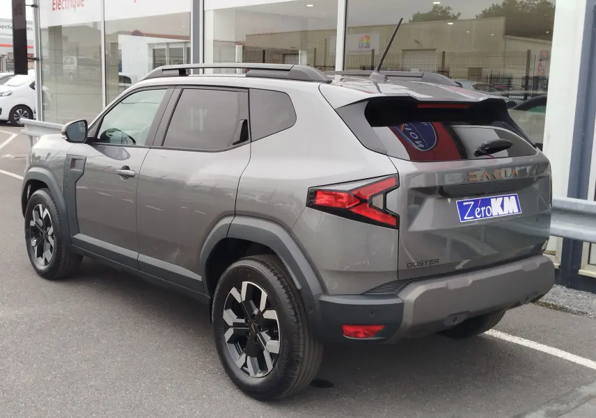 Vue 3/4 arrière droite du Dacia Duster gris schiste 2025 avec jantes noires et détails noirs contrastants.