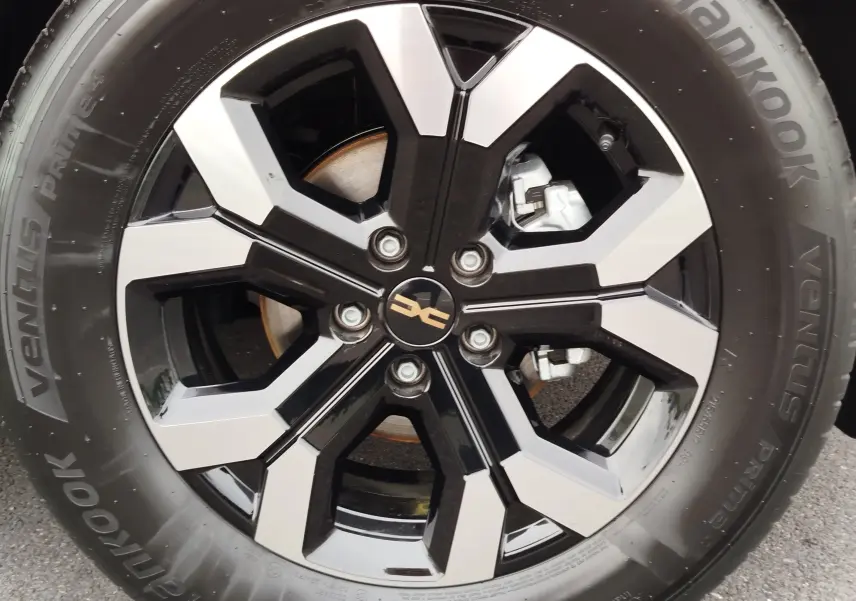 Gros plan sur la jante noire et argentée du Dacia Duster gris schiste avec logo central et pneu Hankook visible.