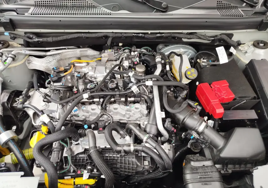 Vue rapprochée du moteur essence du Dacia Duster 2025 gris schiste, montrant câblages et batterie avec capot ouvert.