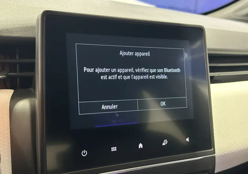 Écran tactile central affichant un message Bluetooth dans l'habitacle clair d'une Renault Clio V gris 2023.