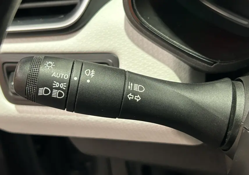 Gros plan sur la commande des feux et clignotants dans l'habitacle gris clair d'une Renault Clio V TCe 90 TECHNO 2023.