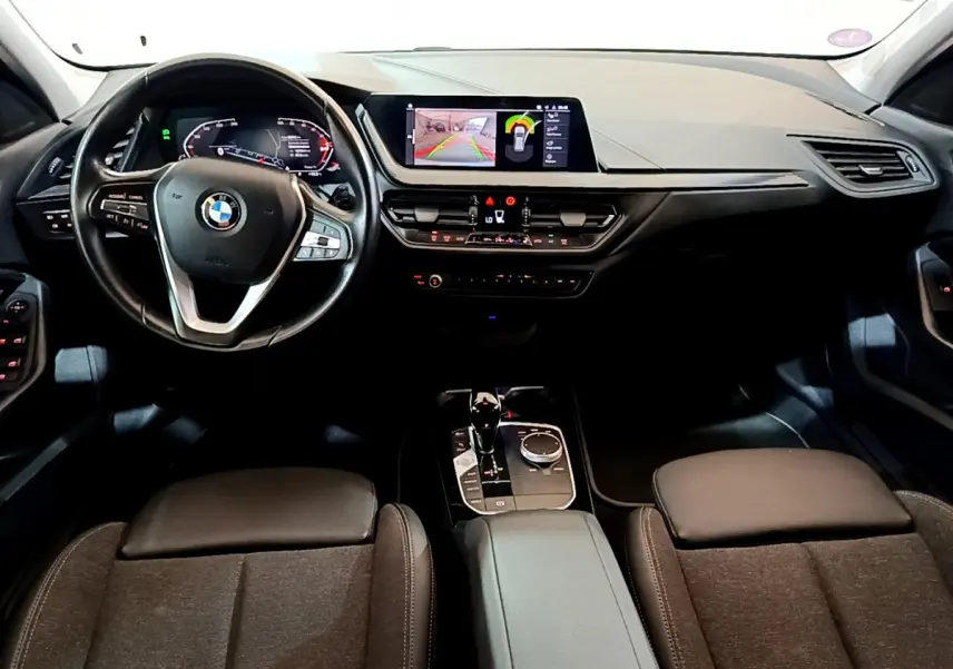 Intérieur BMW Série 1 118i 2021, vue frontale du tableau de bord avec écran central et volant multifonction cuir noir.