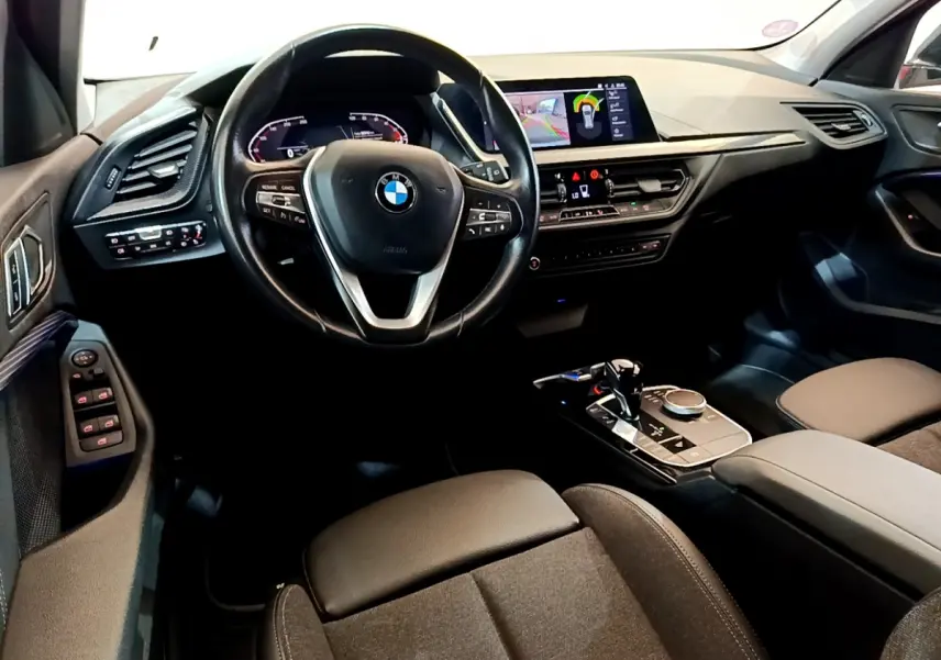 Intérieur de BMW Série 1 118i 2021, vue avant centrée sur volant cuir, tableau de bord digital et console moderne.