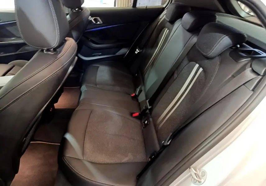 Vue intérieure côté droit sur la banquette arrière noire avec surpiqûres claires d'une BMW Série 1 gris clair 2021.