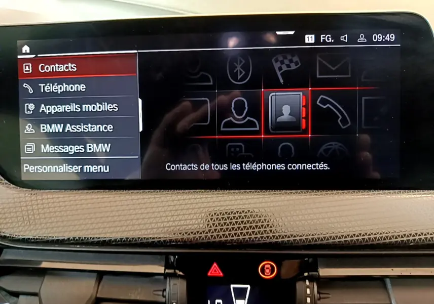 Écran central tactile de la BMW Série 1 2021 affichant le menu contacts avec tableau de bord beige texturé.