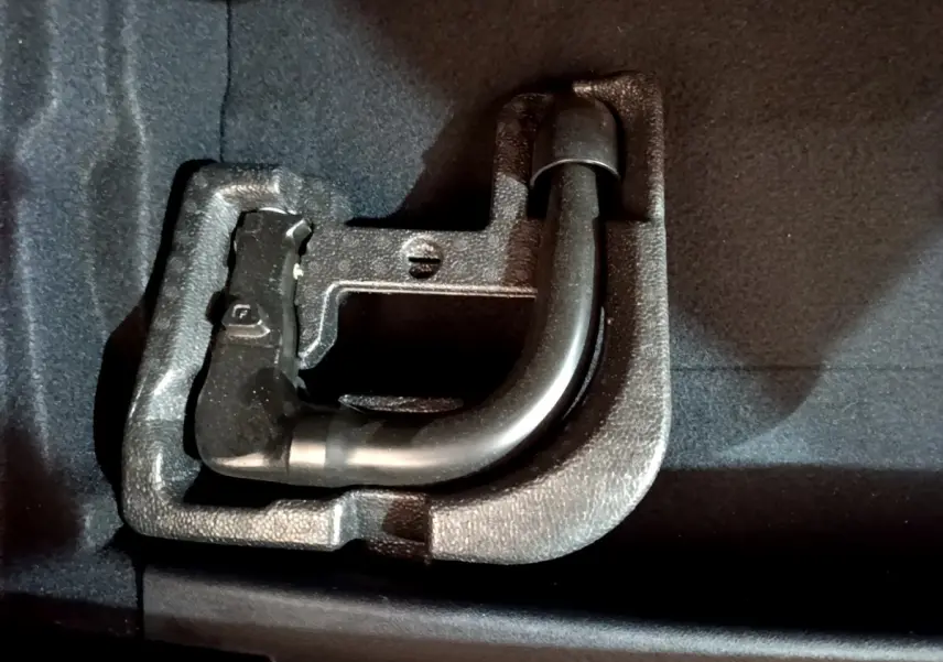 Gros plan sur l'attelage amovible noir logé dans le coffre d'une BMW Série 1 gris clair.