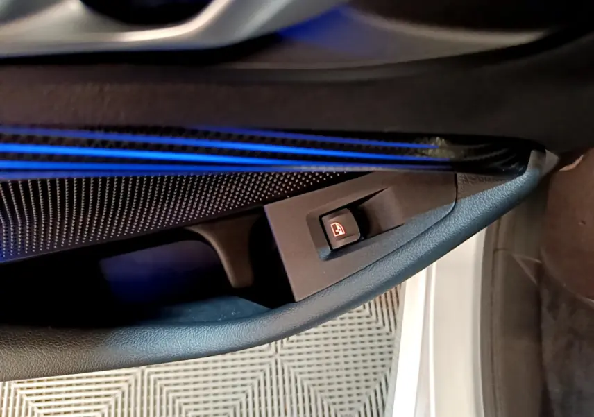 Détail de la portière côté gauche de la BMW Série 1 gris clair, avec éclairage d'ambiance bleu et bouton de verrouillage des vitres.