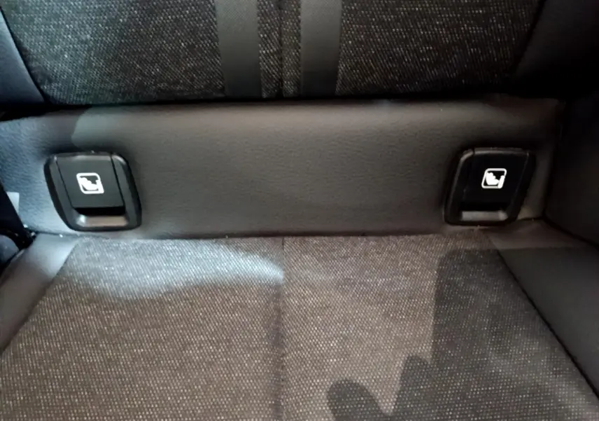 Gros plan sur les commandes de rabattement des sièges arrière en tissu gris foncé d'une BMW Série 1 Edition Sport 2021.