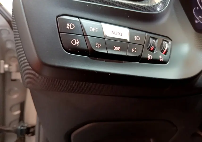 Gros plan sur les commandes d'éclairage à gauche du tableau de bord de la BMW Série 1 gris clair Edition Sport 2021.