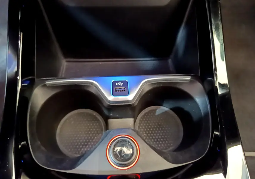 Gros plan sur la console centrale noire de la BMW Série 1 avec porte-gobelets et port USB visible.