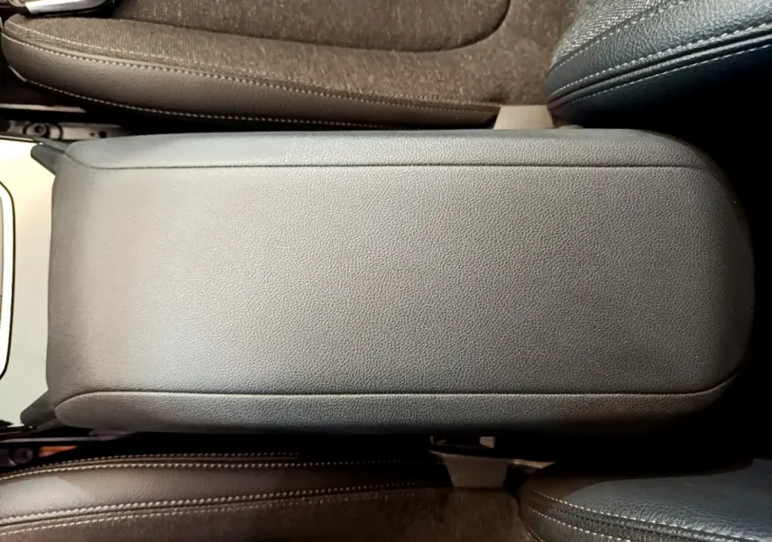 Gros plan sur l'accoudoir central en cuir noir entre les sièges avant d'une BMW Série 1 gris clair.